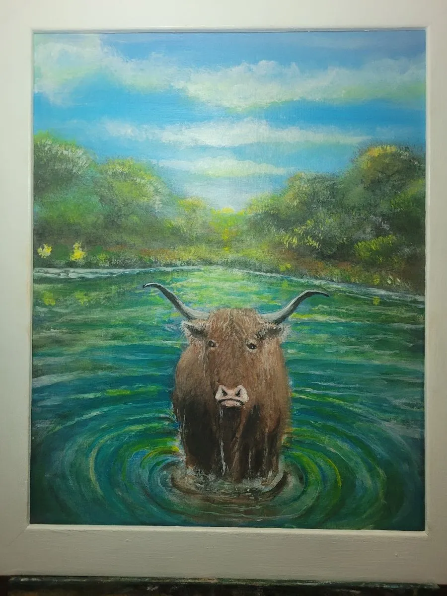 Brown longhorn standing in green and turquoise water with circular ripples and a wooded shore.